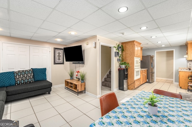 dining room featuring a paneled ceiling, stairs, baseboards, and light tile patterned floors
