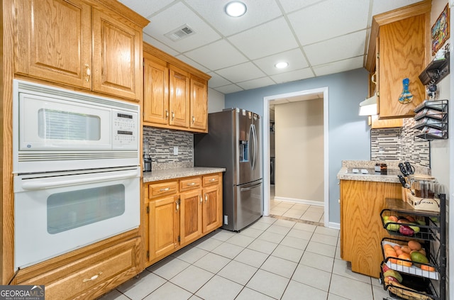 kitchen featuring light tile patterned floors, white appliances, light countertops, and visible vents