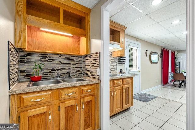 kitchen with light tile patterned floors, backsplash, light countertops, and a sink