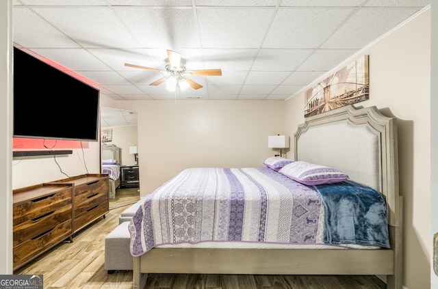 bedroom with a paneled ceiling, a ceiling fan, and wood finished floors
