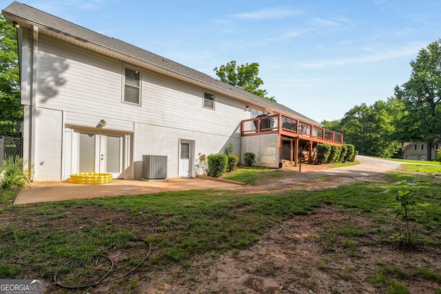 back of property with central AC, a wooden deck, and a patio