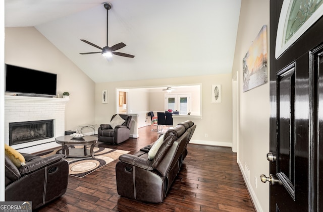 living area featuring baseboards, wood-type flooring, ceiling fan, a brick fireplace, and high vaulted ceiling