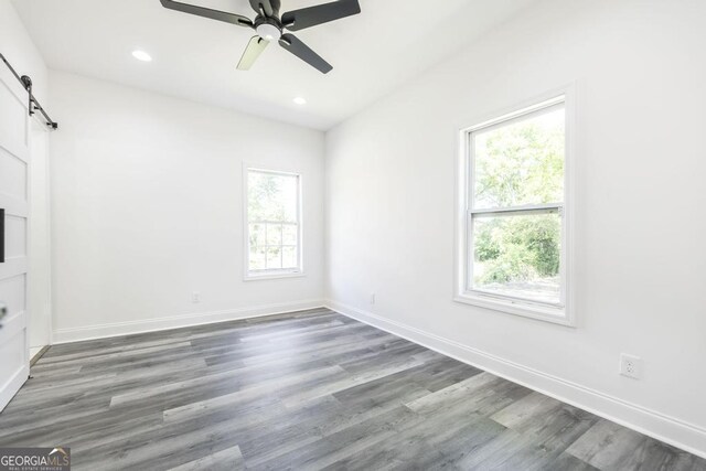 2349 Berthadale Ave, Macon, GA 31204 - empty room featuring wood finished floors, a ceiling fan, baseboards, a barn door, and recessed lighting