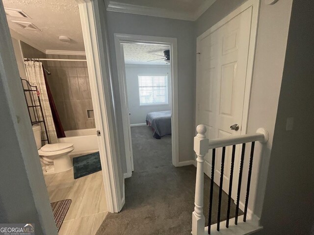 hall with baseboards, ornamental molding, an upstairs landing, and a textured ceiling