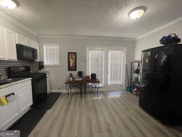 kitchen with white cabinetry, light wood-style floors, black appliances, and a textured ceiling