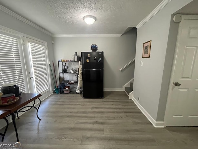 interior space featuring wood finished floors, crown molding, a textured ceiling, baseboards, and stairs