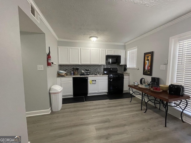 kitchen featuring a textured ceiling, light wood finished floors, visible vents, black appliances, and white cabinets