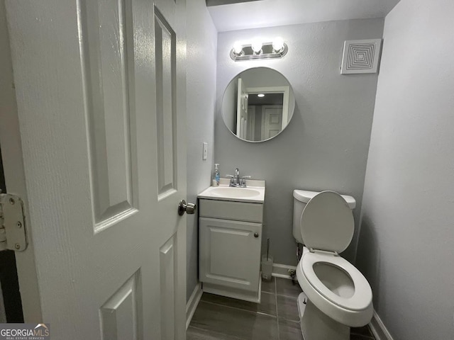 half bathroom with toilet, vanity, visible vents, tile patterned floors, and baseboards