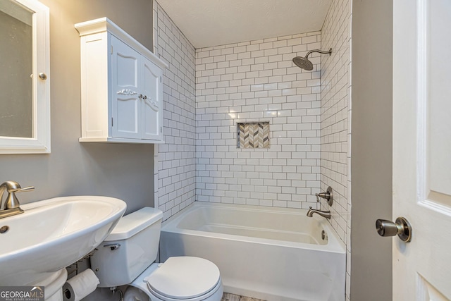 bathroom featuring toilet, shower / bath combination, and a sink