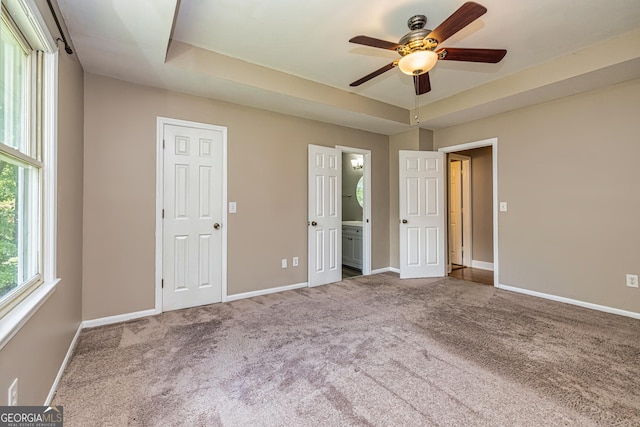 unfurnished bedroom featuring baseboards, a tray ceiling, and carpet floors