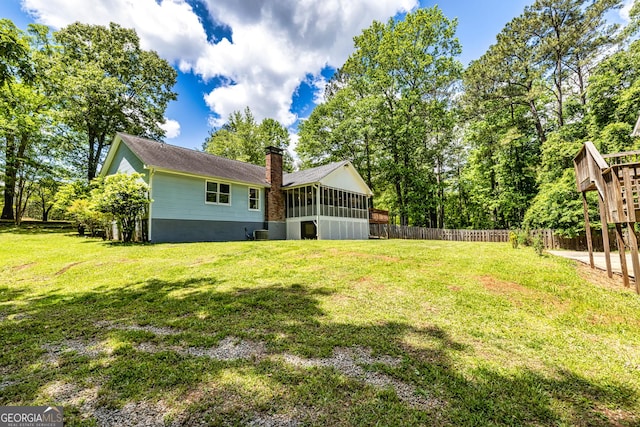 view of yard with a sunroom and fence