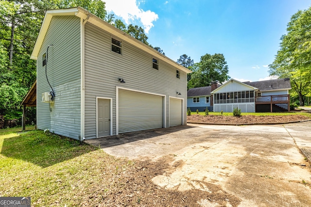 view of property exterior featuring concrete driveway, a sunroom, and a garage