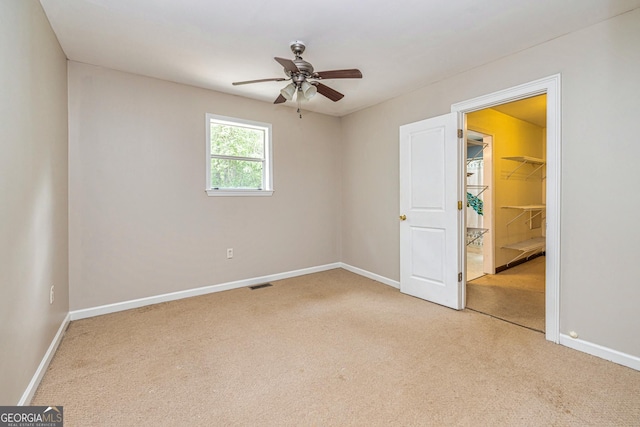 unfurnished room featuring baseboards, light carpet, visible vents, and a ceiling fan