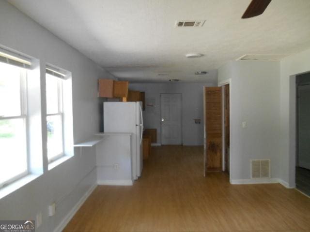 corridor with visible vents, light wood-style flooring, and baseboards