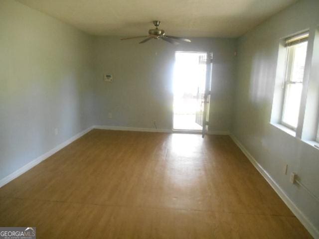 unfurnished room with a wealth of natural light, baseboards, and a ceiling fan