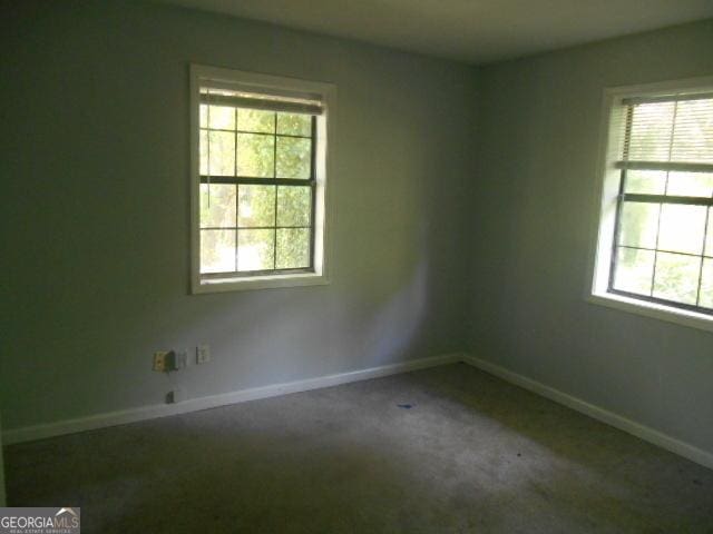 carpeted spare room featuring plenty of natural light and baseboards