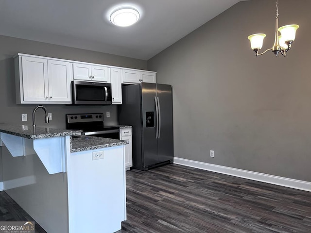 kitchen with a peninsula, dark stone countertops, stainless steel appliances, white cabinets, and dark wood-style flooring