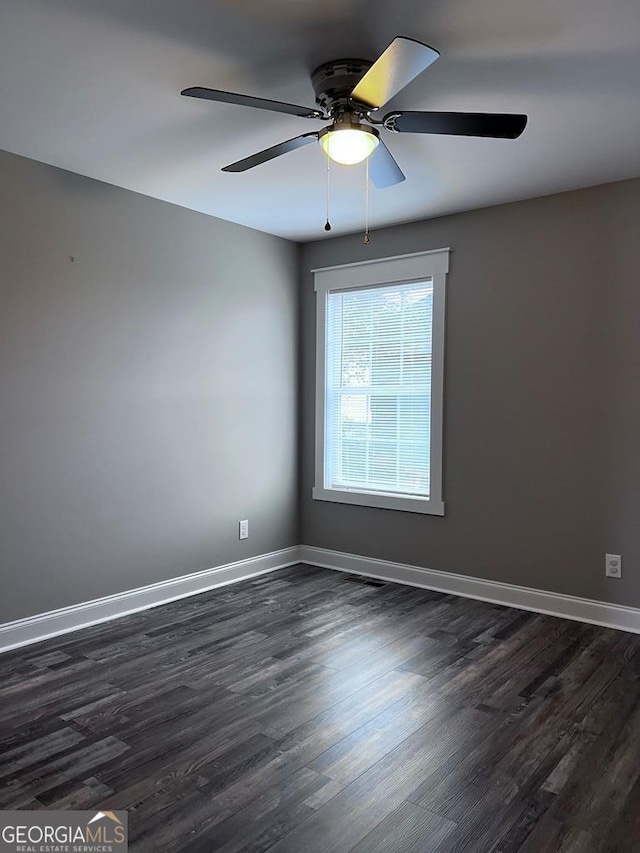 empty room featuring a ceiling fan, dark wood-style flooring, and baseboards