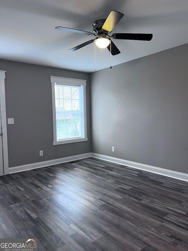empty room featuring dark wood finished floors, baseboards, and ceiling fan