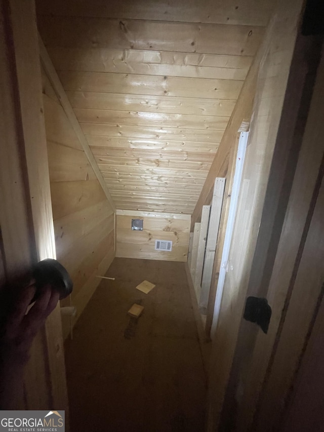 additional living space with wood walls, wood ceiling, and visible vents