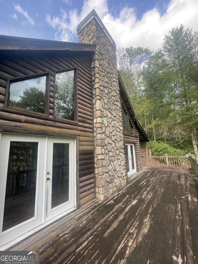view of property exterior featuring a chimney, a deck, and french doors