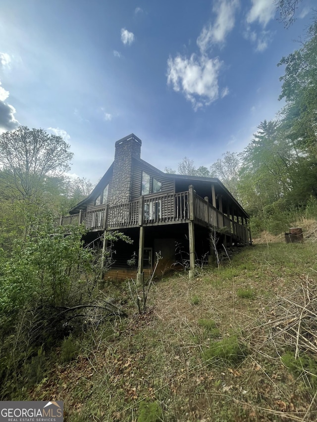 rear view of property with a chimney and a wooden deck