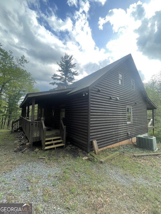 view of home's exterior featuring central AC unit, a wooden deck, and log veneer siding