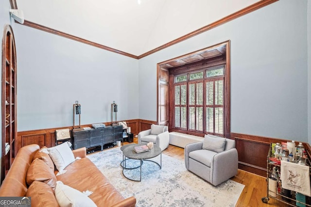 living room with wainscoting, vaulted ceiling, wood finished floors, and ornamental molding