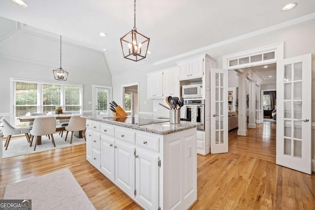 kitchen featuring stainless steel oven, black electric stovetop, a chandelier, french doors, and a kitchen island