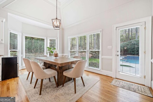 dining space with light wood-style floors, a chandelier, beam ceiling, and wainscoting