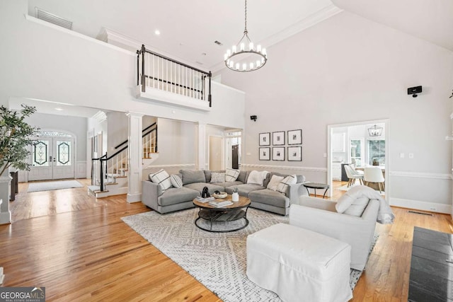 living room with high vaulted ceiling, a chandelier, wood finished floors, stairs, and ornamental molding