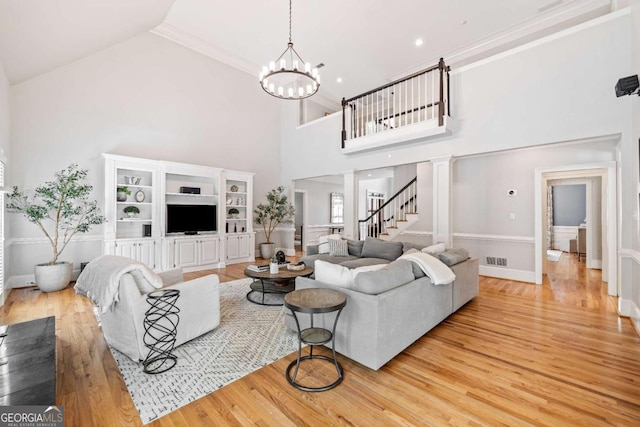 living area featuring a chandelier, light wood finished floors, high vaulted ceiling, decorative columns, and baseboards