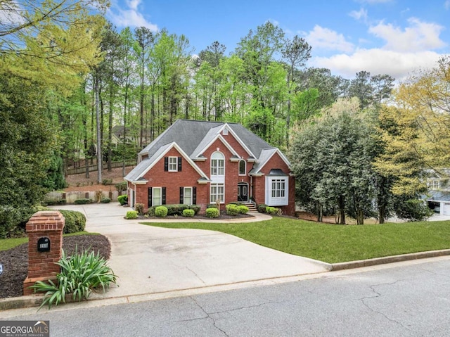 view of front of house with concrete driveway, brick siding, and a front lawn