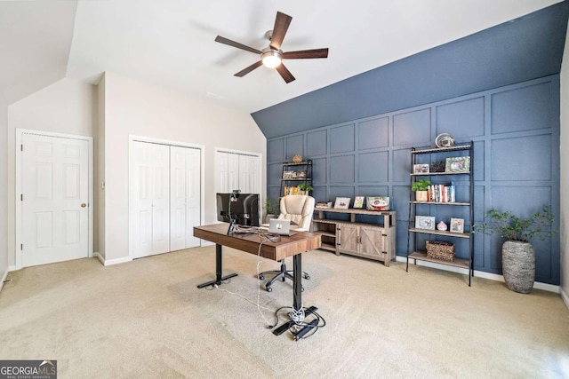 office space with a decorative wall, light carpet, ceiling fan, and lofted ceiling