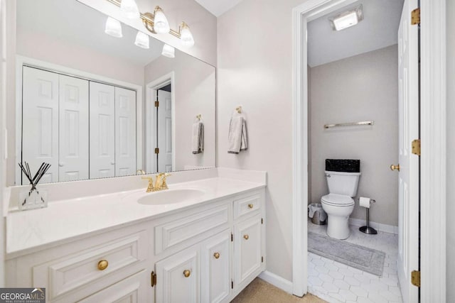 bathroom with toilet, vanity, baseboards, and tile patterned flooring
