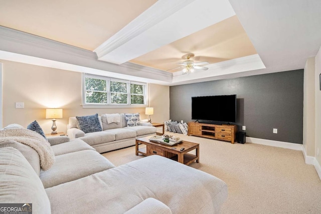 living area featuring ceiling fan, baseboards, a raised ceiling, carpet flooring, and ornamental molding