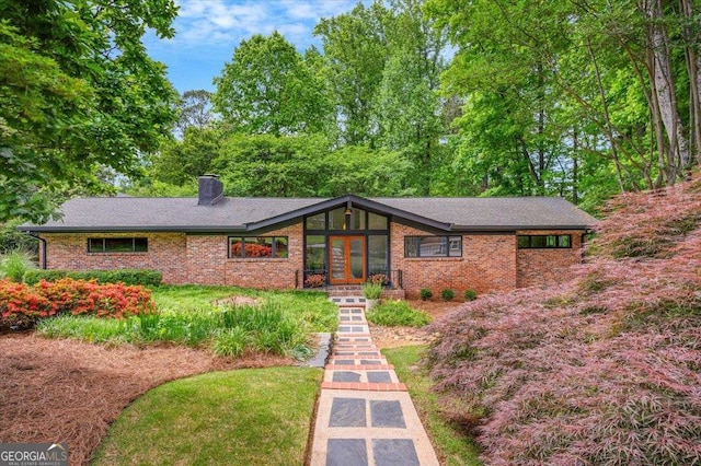 mid-century modern home with french doors, brick siding, and a chimney