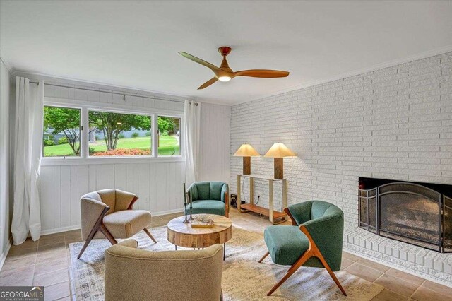 sitting room featuring a fireplace, ceiling fan, crown molding, and tile patterned flooring
