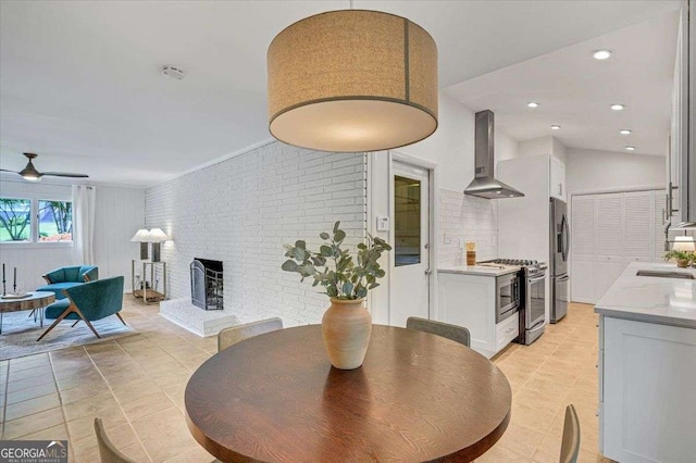 dining room featuring a brick fireplace, light tile patterned floors, and ceiling fan