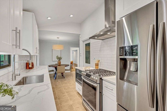 kitchen featuring stainless steel appliances, wall chimney exhaust hood, decorative backsplash, white cabinets, and vaulted ceiling