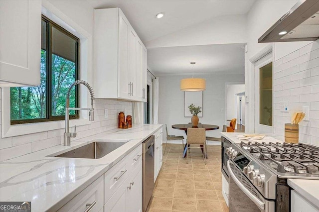 kitchen featuring a sink, stainless steel appliances, decorative backsplash, white cabinetry, and range hood