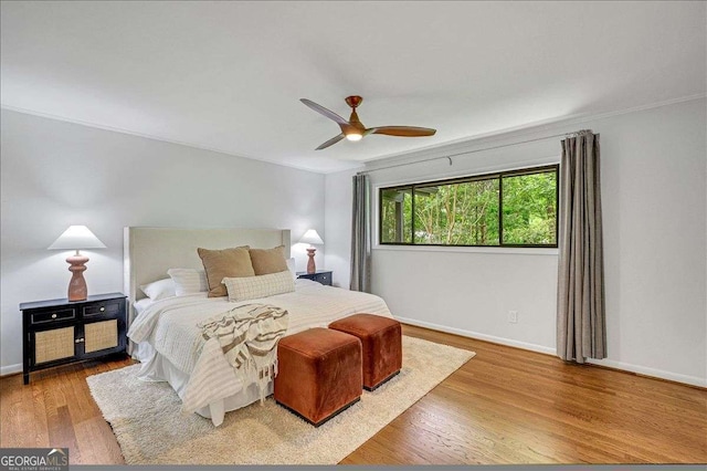 bedroom featuring wood finished floors, baseboards, ornamental molding, and a ceiling fan