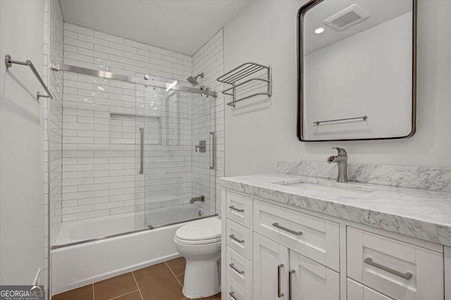 full bath featuring toilet, tile patterned floors, vanity, and shower / bath combination with glass door