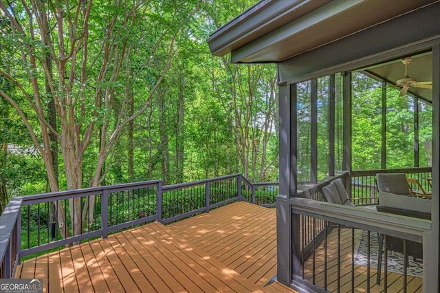 wooden deck with a sunroom and a wooded view