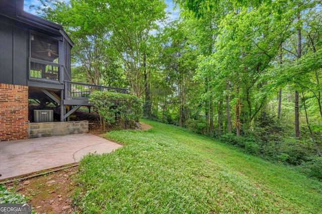 view of green lawn with a patio, a sunroom, a deck, and cooling unit