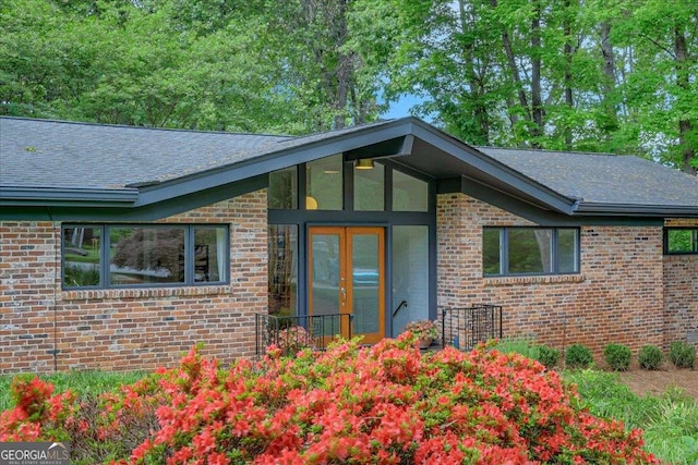 view of side of property featuring brick siding and a shingled roof