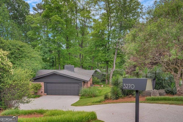 view of front facade featuring a garage, a chimney, and driveway