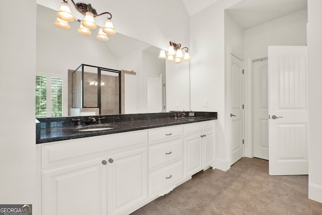 bathroom with vaulted ceiling, a chandelier, a stall shower, and double vanity