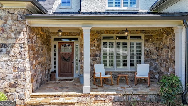 doorway to property with stone siding and covered porch