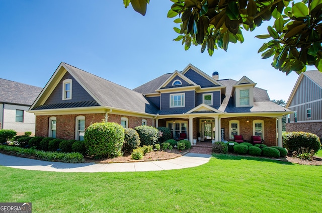 1340 Traditions Way, Jefferson, GA 30549 - craftsman-style home featuring brick siding, covered porch, a front lawn, roof with shingles, and a chimney
